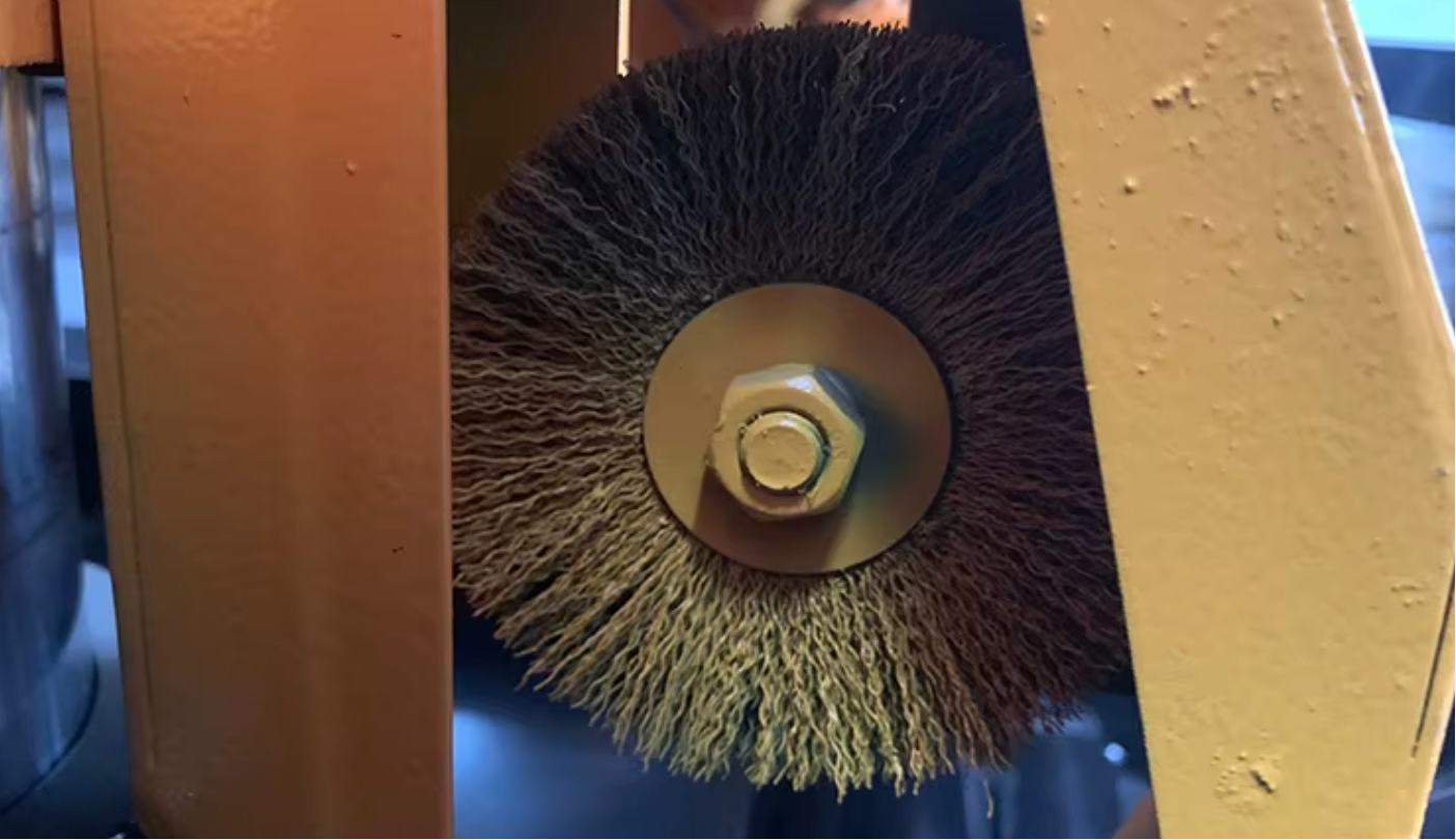 A wire brush cleaning chips from a band saw blade's teeth